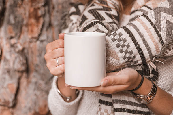 Mulher de cultivo com caneca perto de árvore