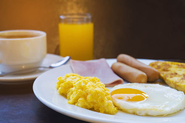 Pequeno-almoço inglês com ovos, salsichas, charcutaria e café.