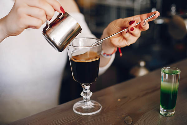 Mulher com uma camisola branca a deitar leite na sobremesa do café