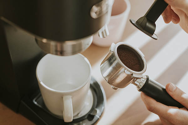 Barista a prensar café moído num filtro de café de máquina