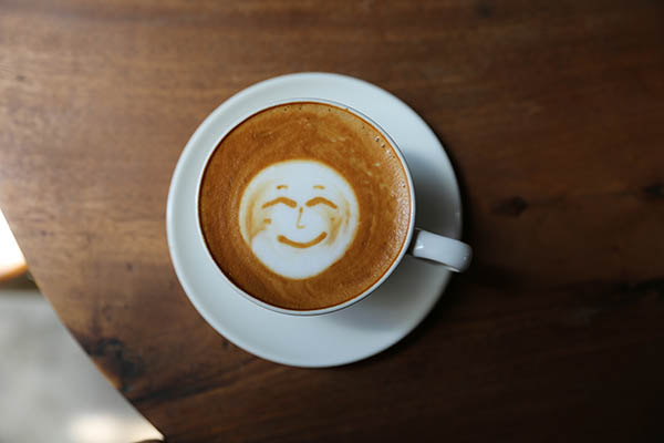 Taça de cappucino quente e saboroso com um sorriso de latte de arte. 