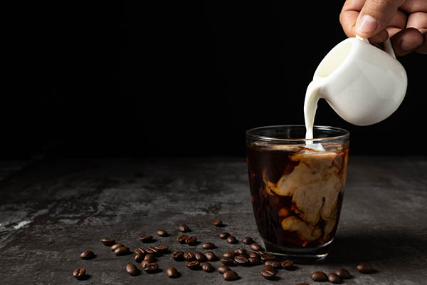 Leite a verter em café preto gelado.